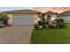 Charming home featuring a well-manicured lawn, complemented by lush landscaping, and a two-car garage for convenient parking at 6442 Bendelow Dr, Lakeland, FL 33810