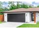 Attached garage featuring a dark garage door, brick exterior, and manicured lawn at 1820 N Merrick Dr, Deltona, FL 32738