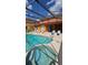 Enclosed pool and hot tub with ample seating, surrounded by an orange home exterior and blue skies at 153 Tigerlily Ct, Davenport, FL 33837