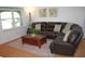 Cozy living room with a dark leather sofa, area rug, and large sunny window at 20732 Sw Marine Blvd, Dunnellon, FL 34431