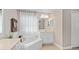 Bright bathroom with a garden tub under a window and a vanity with white cabinets at 460 Tess Ct, Orlando, FL 32834