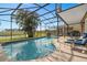 Sparkling screened-in pool area featuring a paver deck, lush palm trees, and serene water views at 460 Tess Ct, Orlando, FL 32834