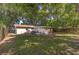 Spacious backyard with mature trees, a patio with seating, and a wooden privacy fence at 5932 Hilltop E Ln, Lakeland, FL 33809