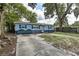 Charming single story home with blue painted wood siding and a long driveway in a lush and wooded lot at 5932 Hilltop E Ln, Lakeland, FL 33809