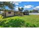 Spacious backyard featuring a screened in porch, lush green grass, and mature trees underneath a blue sky at 4821 S Gachet Blvd, Lakeland, FL 33813