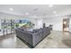 Bright living room with large gray sectional sofa, tile floors, and a view through the large window at 4821 S Gachet Blvd, Lakeland, FL 33813