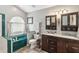 Bathroom with double sinks, dark cabinetry, and an arched window above the tub at 25302 Lido Ave, Sorrento, FL 32776