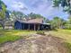Wide backyard with the house featuring an extensive covered patio surrounded by trees, plants, and landscaping at 2900 Cr 415, Lake Panasoffkee, FL 33538