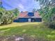 View of the back of the dark blue house surrounded by a lush lawn and palm trees at 2900 Cr 415, Lake Panasoffkee, FL 33538