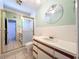 Full bathroom featuring a shower with a glass door, white tile, vanity, and round mirror at 2900 Cr 415, Lake Panasoffkee, FL 33538