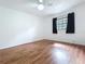 Bedroom features wood floors, ceiling fan, and a window with black curtains at 2900 Cr 415, Lake Panasoffkee, FL 33538