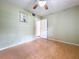Bedroom with light green walls, wood floors, ceiling fan, and open doorway to another room at 2900 Cr 415, Lake Panasoffkee, FL 33538