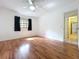 Bright bedroom featuring wood floors, fan, window with dark curtains, and ensuite bath at 2900 Cr 415, Lake Panasoffkee, FL 33538