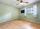 Bedroom with light green walls, wood floors, ceiling fan, and a window with white curtains at 2900 Cr 415, Lake Panasoffkee, FL 33538