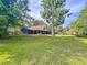 A captivating view of the house from its yard, surrounded by lush green grass and various trees at 2900 Cr 415, Lake Panasoffkee, FL 33538
