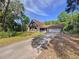 Stone house with a driveway, garage, and second story deck surrounded by trees in a lush, green yard at 2900 Cr 415, Lake Panasoffkee, FL 33538