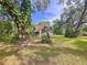 Landscaped front yard with mature trees, featuring a charming home with stone accents and a garage at 2900 Cr 415, Lake Panasoffkee, FL 33538