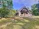 A-frame home with stone accents, balcony, and fenced yard, surrounded by mature trees and green grass at 2900 Cr 415, Lake Panasoffkee, FL 33538