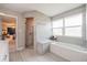 Bright bathroom featuring gray tiled walls, glass enclosed shower, soaker tub, and a connecting bedroom at 1416 Leighton Ave, Lakeland, FL 33803