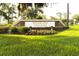 The Woodland Villages community sign with lush flowers is surrounded by an expansive green lawn at 2418 Se 23Rd St, Ocala, FL 34471