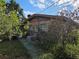 Backyard view showing AC units, trees, bushes, and a brick exterior with visible air conditioning units at 115 Marjorie Ave, Auburndale, FL 33823