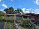 A single-story brick home with a covered entrance, surrounded by a vibrant, overgrown garden with lush greenery at 115 Marjorie Ave, Auburndale, FL 33823