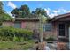Brick home exterior showing the front entrance and overgrown garden with a blue sky and white clouds at 115 Marjorie Ave, Auburndale, FL 33823