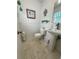 Bright bathroom with decorative accents, featuring a pedestal sink, wainscoting, and tiled floors at 1618 Pineberry St, Lakeland, FL 33803