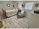 Cozy bedroom with natural light, a patterned floral quilt, a sitting area, and gray wood-look floors at 1618 Pineberry St, Lakeland, FL 33803