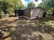 Backyard of the home with privacy fence, lush green grass, mature trees and a small porch at 2434 Trenton E Rd, Lakeland, FL 33815