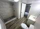 Bathroom showcasing the upgraded shower and new gray vinyl plank flooring at 2434 Trenton E Rd, Lakeland, FL 33815