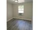 Bedroom with a window and air conditioning unit, featuring new gray vinyl plank flooring at 2434 Trenton E Rd, Lakeland, FL 33815