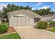Attached garage with a wide concrete driveway and manicured landscaping including flowers at 2121 Escobar Ave, Lady Lake, FL 32159