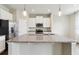 Close up of a granite kitchen island with a stainless steel sink, stylish pendant lights and white cabinets in view at 392 Summer Squall Rd, Davenport, FL 33837
