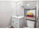 Well-lit bathroom with a white vanity, marble countertop, modern fixtures, and convenient shelf storage at 1002 Ne 1St St, Mulberry, FL 33860
