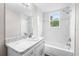 Bright bathroom featuring a white vanity with marble countertop, tub and shower combo with dual shower heads, and tiled walls at 1002 Ne 1St St, Mulberry, FL 33860