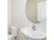 Clean bathroom features a white sink, toilet, and a round mirror at 3775 King Hill Dr, Haines City, FL 33844