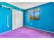 Bright blue bedroom with a window overlooking green trees and purple carpet at 728 Waterbridge Dr, Winter Haven, FL 33880