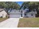 Charming single-Gathering home featuring a two-car garage, blue trim, and beautiful mature trees at 748 Sagewood Dr, Lakeland, FL 33813