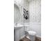 Modern powder room featuring a pedestal sink, patterned wallpaper, and white subway tile at 4027 Gardenia Ave, Lake Hamilton, FL 33851