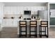 Bright and modern kitchen featuring white cabinetry, stainless steel appliances, a large center island, and stylish bar stools at 4027 Gardenia Ave, Lake Hamilton, FL 33851