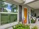 Charming covered porch with seating, an orange front door, and lush landscaping at 4730 Se 141St Pl, Summerfield, FL 34491