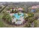 Aerial view of the community pool, surrounded by lush landscaping, palms, and a clubhouse at 1839 Via Lago Dr, Lakeland, FL 33810