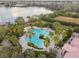Aerial view of the community pool area, featuring palm trees, lounging chairs, and a clubhouse at 1839 Via Lago Dr, Lakeland, FL 33810
