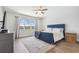 Bright bedroom with a blue bed, wooden floors, and a large window offering views of the green outdoors at 1839 Via Lago Dr, Lakeland, FL 33810
