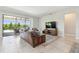 Comfortable living room featuring a leather couch, television, ceramic tile flooring, and a view of the pool at 1839 Via Lago Dr, Lakeland, FL 33810