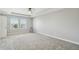 Bright carpeted bedroom with a tray ceiling, ceiling fan, and large windows at 4950 Chase Ct, St Cloud, FL 34772