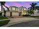Elegant two-story home with a brick driveway, lush landscaping, and a three-car garage at twilight at 4950 Chase Ct, St Cloud, FL 34772