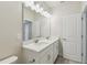 Bathroom with white cabinets, double sinks, large mirror, and doorway at 6690 Wake St, St Cloud, FL 34771