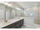 Bathroom with gray cabinets, double sinks, large mirror, tiled shower with window at 6690 Wake St, St Cloud, FL 34771